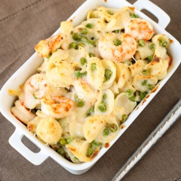 Creamy Gruyere and Shrimp Pasta with Peas in baking dish with spoon.