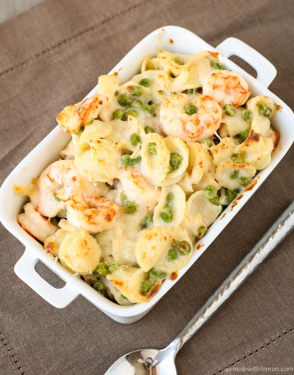 Creamy Gruyere and Shrimp Pasta with Peas in baking dish with spoon.