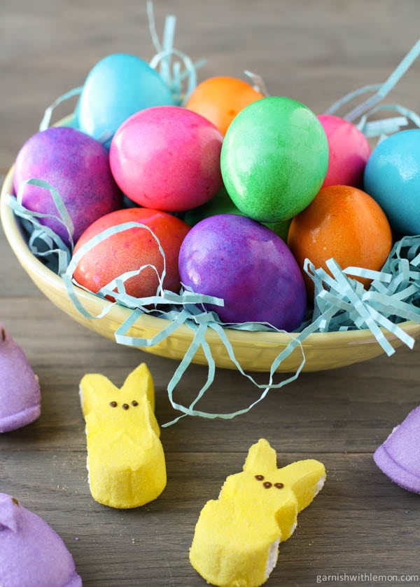 Boiled eggs in bowl that have been colored, with peeps.