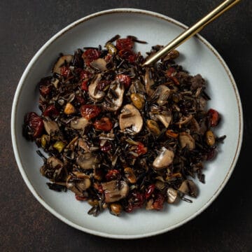 A bowl of wild rice with cranberries and mushrooms.