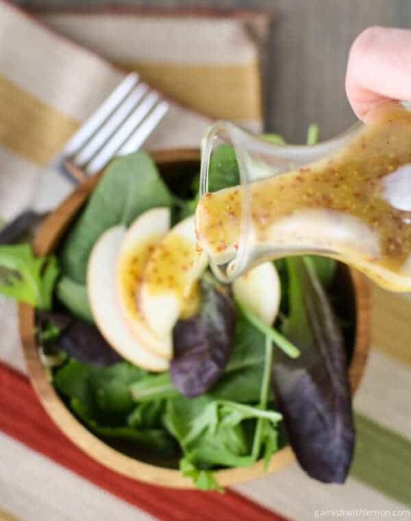 Dijon Vinaigrette pouring on salad.