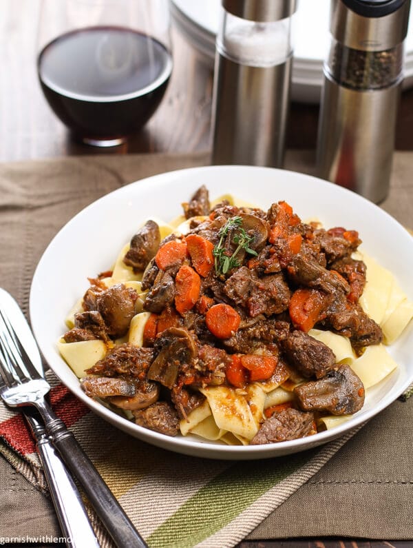 Beef Provencal on a table with wine.