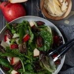 A bowl of fruit and green salad, with pears and parmesan.