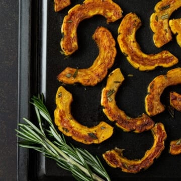 sliced squash on sheet pa, with rosemary.