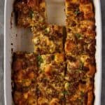 white baking dish with sausage egg bake cut into squares and ready to serve.