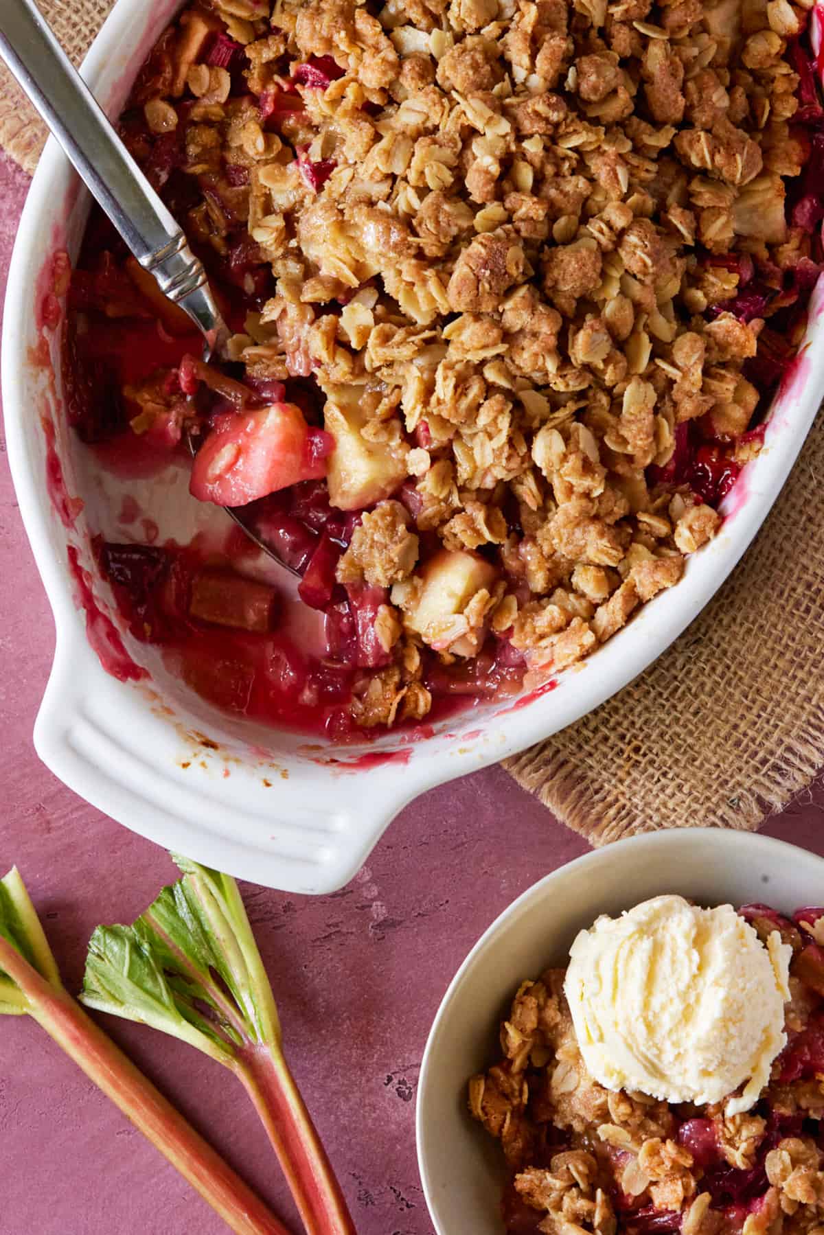 baking dish filled with fruit crisp with bowl full of crisp and ice cream.