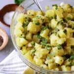 Bowl of potato salad with parsley and capers.