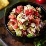 avocado salsa in black bowl with chips.