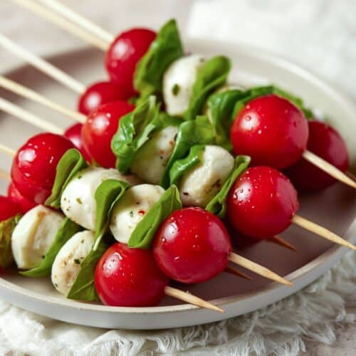 Caprese skewers stacked on top of each other on a gray plate.