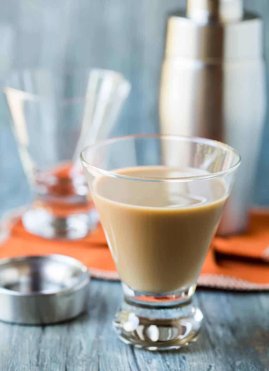 A close up of a glass cup on a table, with Kahlúa and Schnapps.