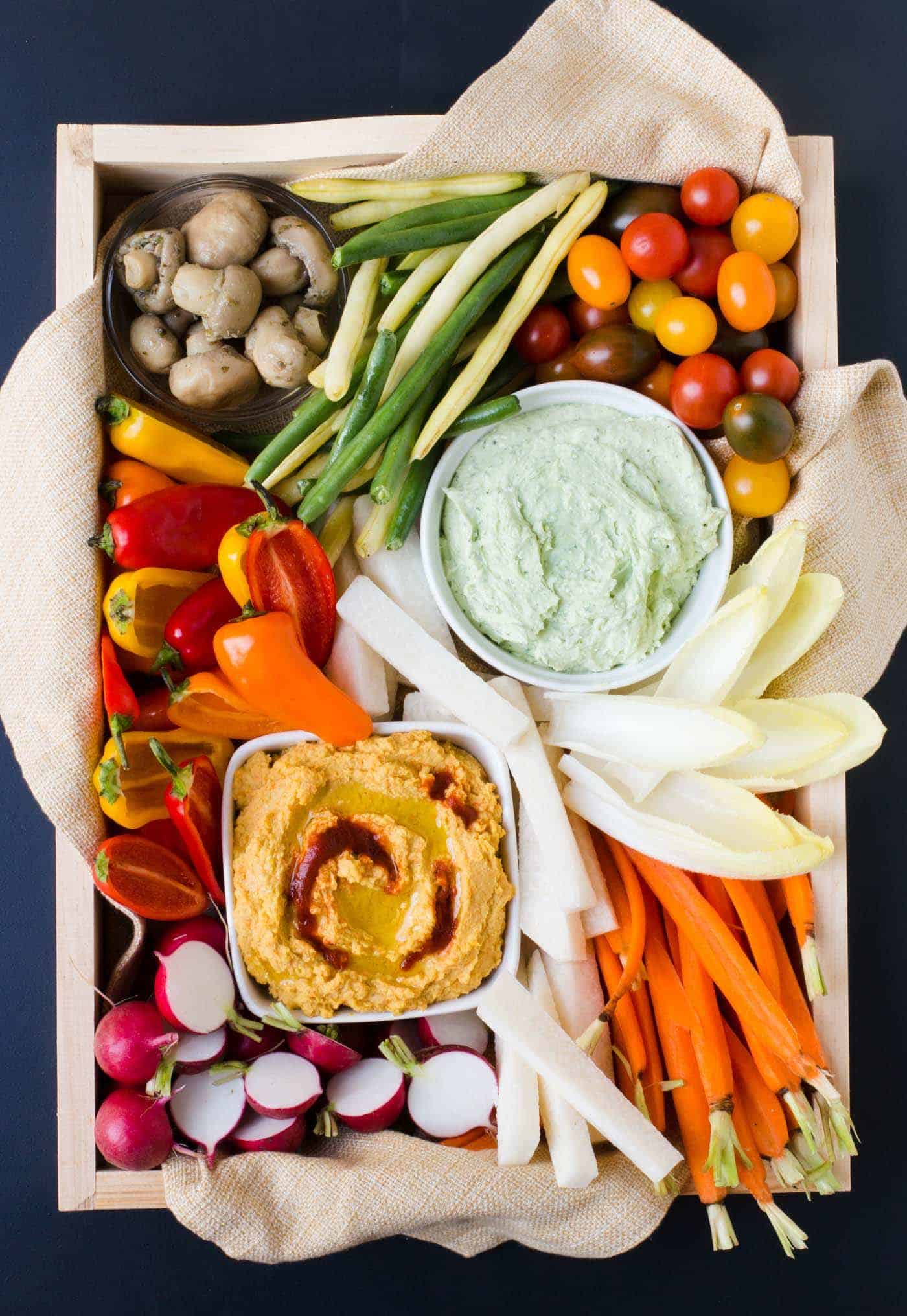 A tray filled with fresh vegetables and dips.