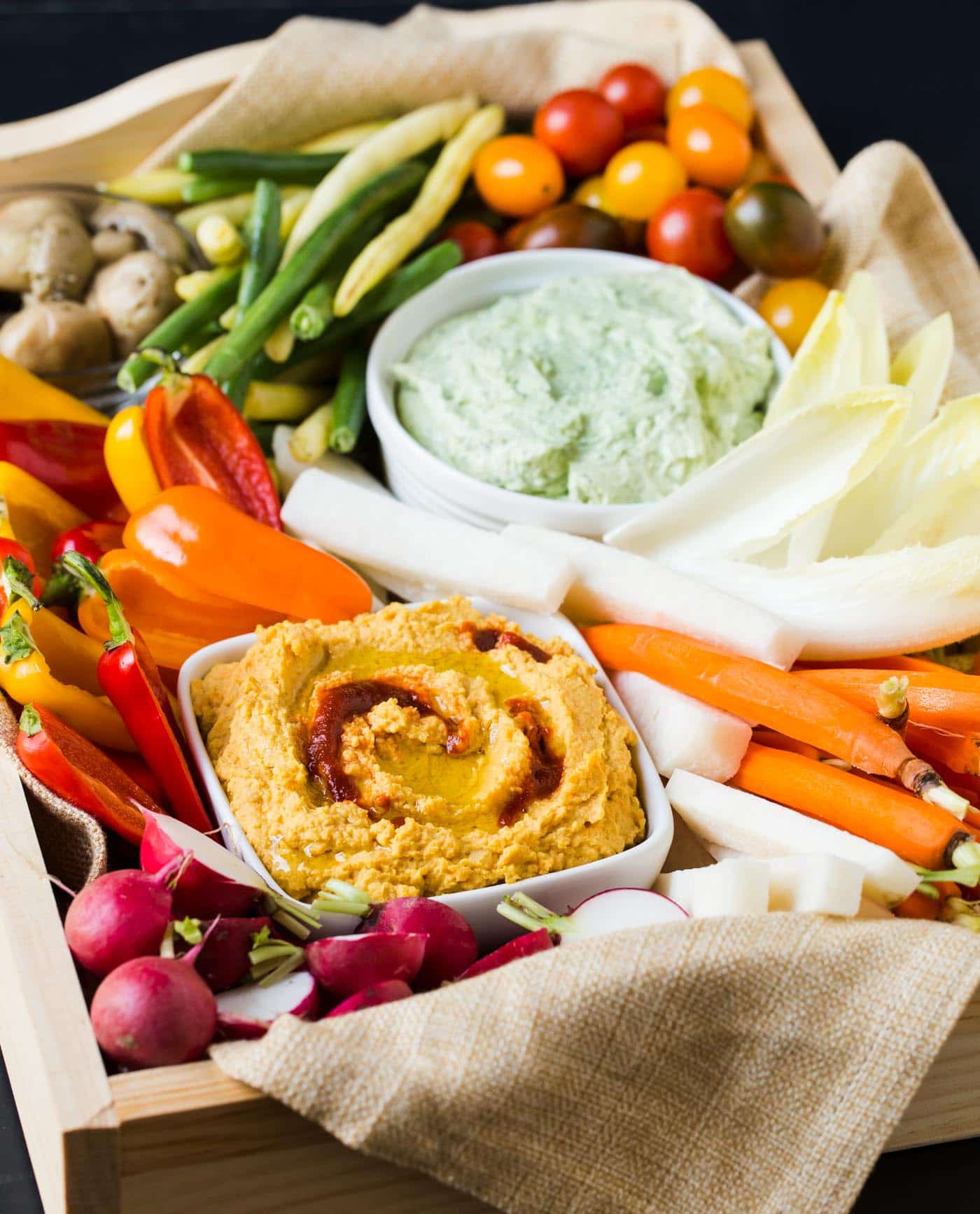 A tray of vegetables and dips on a table.