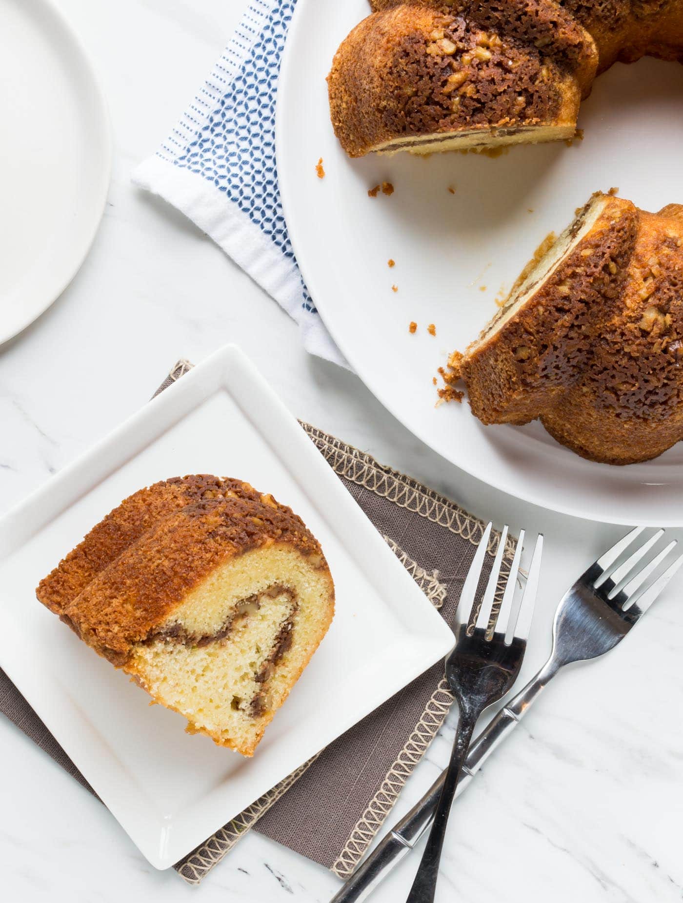 A piece of cake on a plate, with Coffee cake on bigger plate.