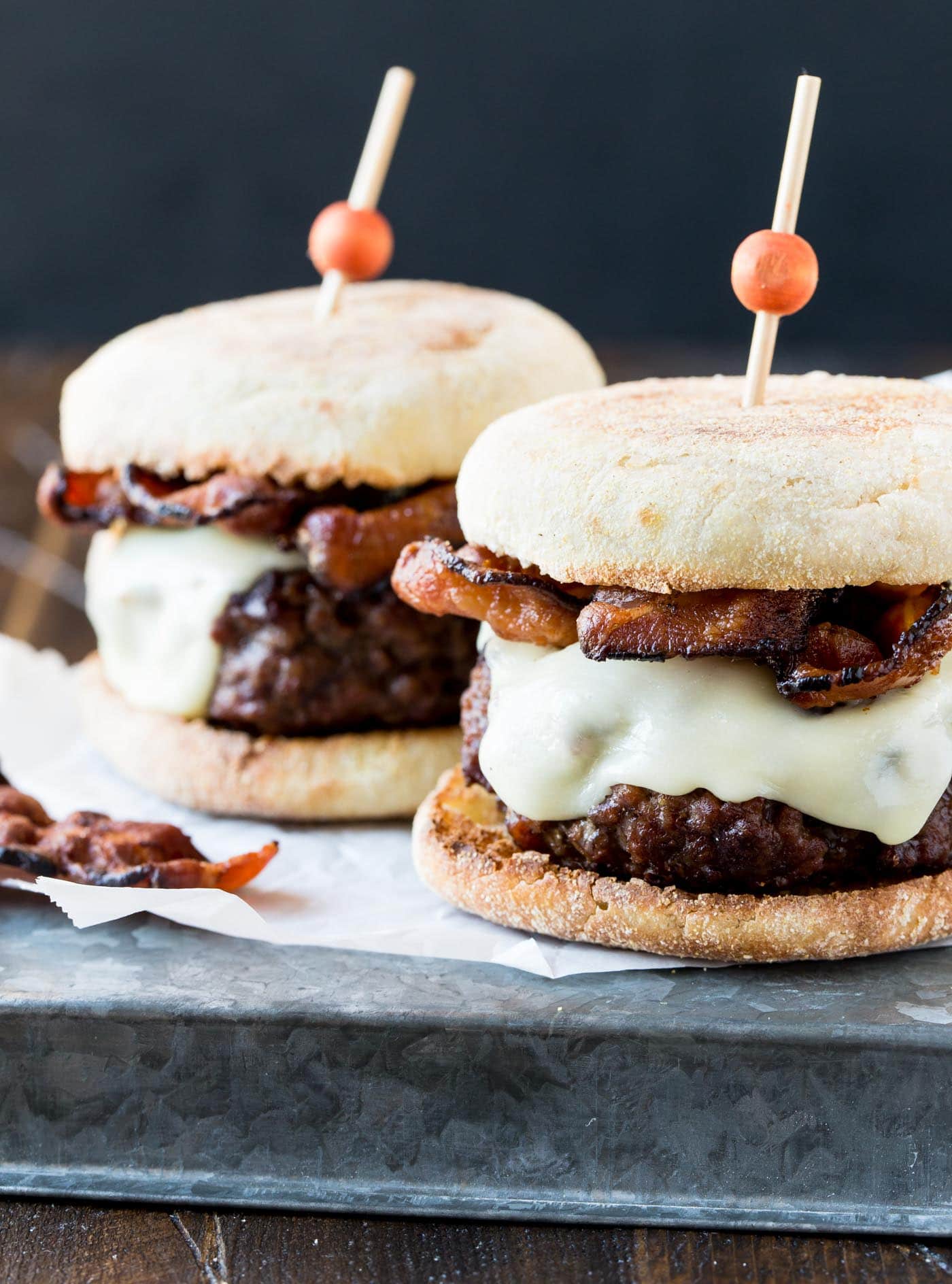 Two Guinness Burgers with Irish Cheddar and Bacon. Both burgers are skewered with tall toothpicks to hold them together. 