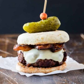 Burger with Irish Cheddar and Bacon on a toasted English muffin and topped with a mini gherkin pickle.