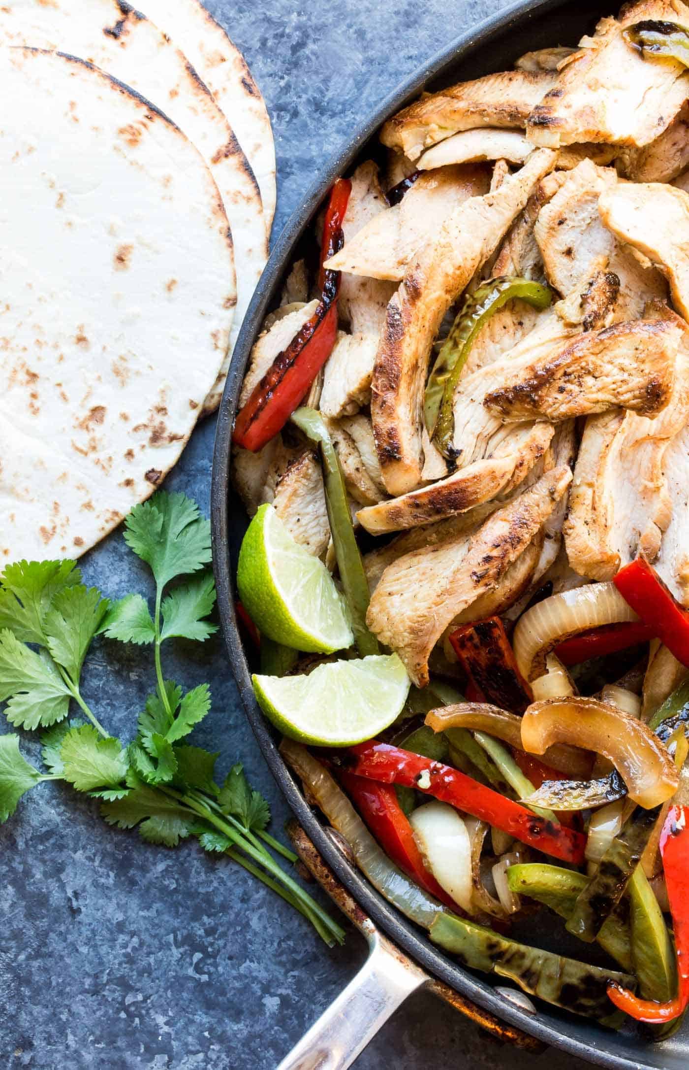 Chicken fajitas in pan with tortillas.