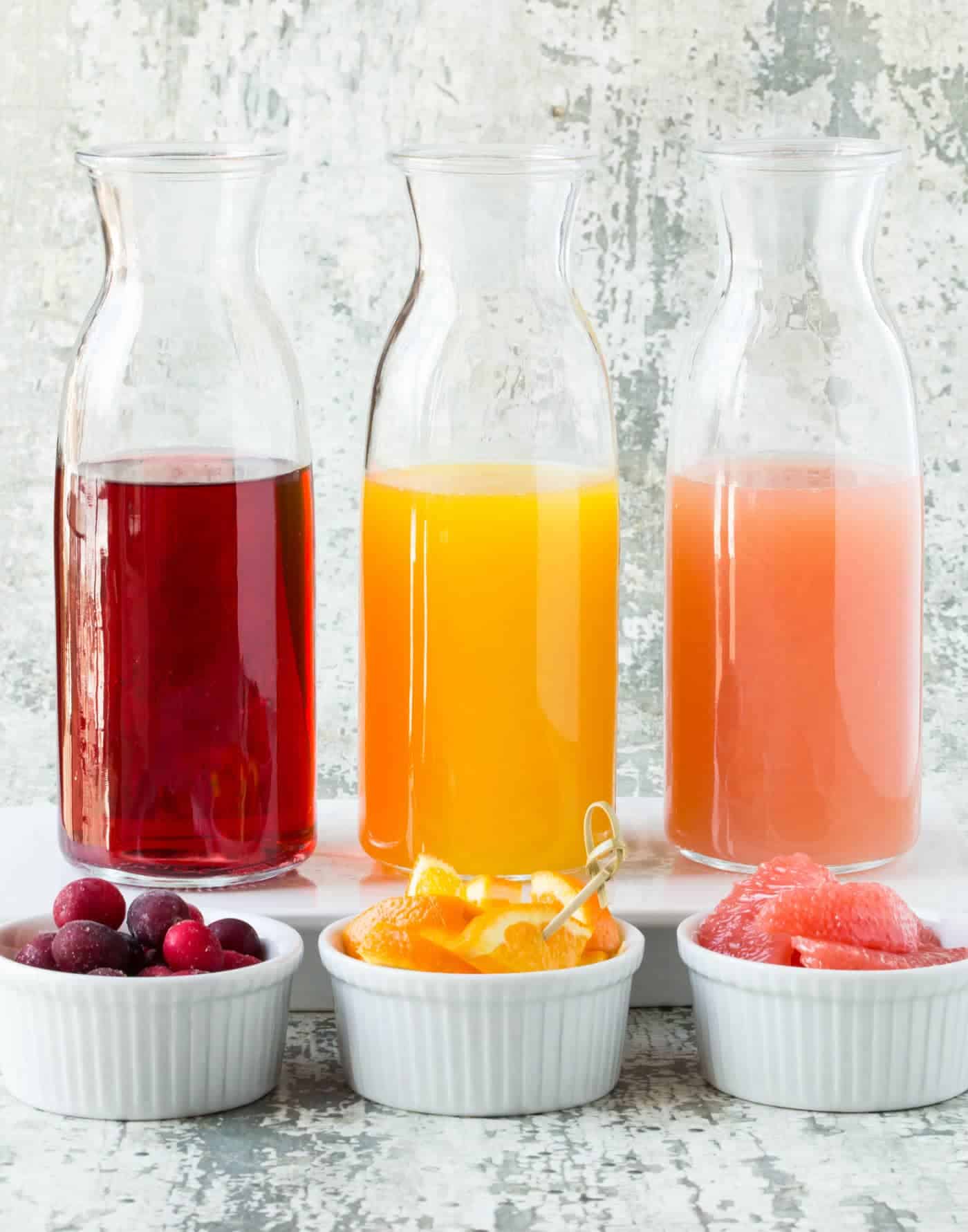 Glass bottles filled with juices with fresh fruit.