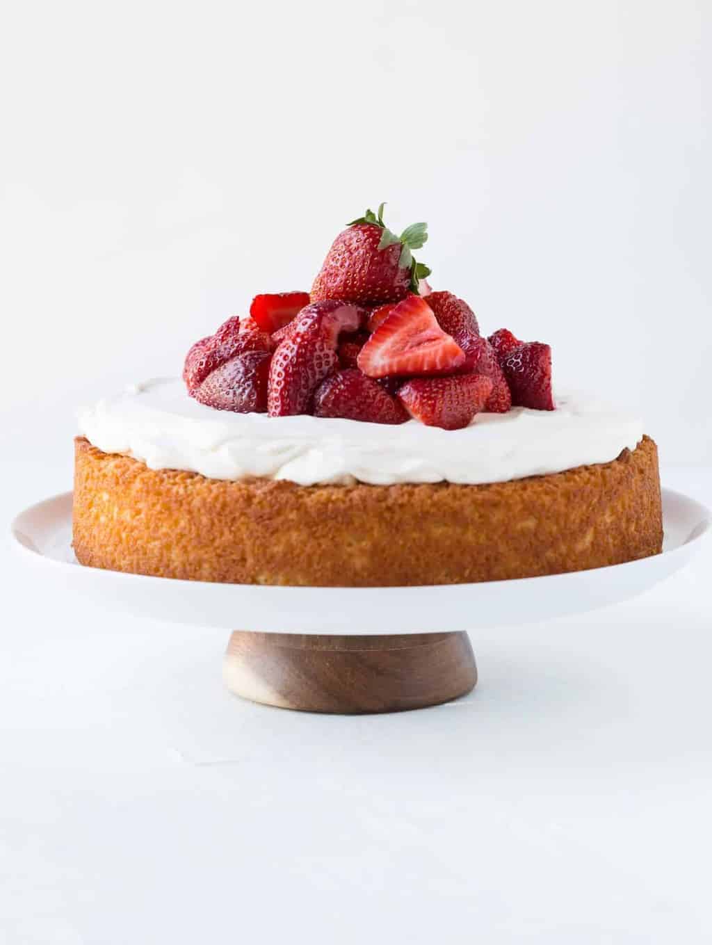 A cake on a platter topped with strawberries and cream.