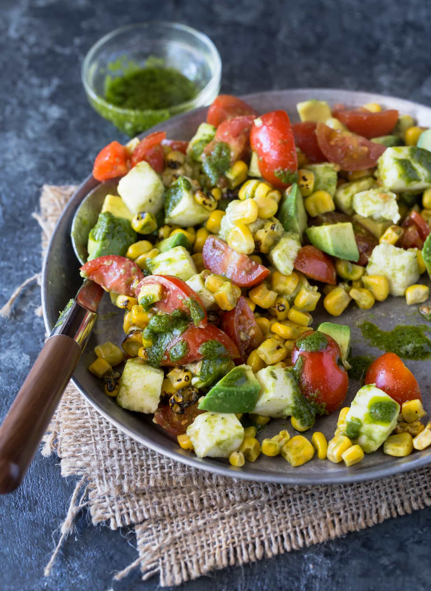 Silver bowl filled with Tomato, Mozzarella and Grilled Corn Salad with cilantro lime dressing.