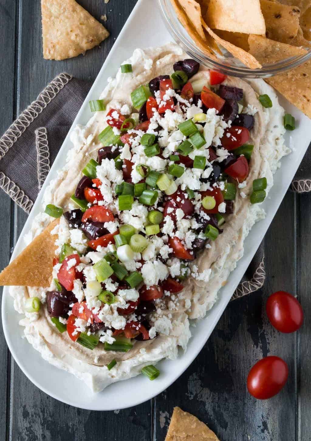 Greek Dip on a white platter with a bowl of pita chips.