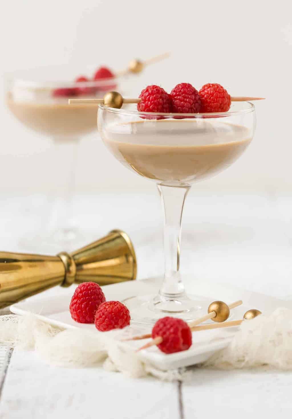 Chocolate Raspberry Martinis in coupe glasses with fresh raspberries threaded on skewer for garnish.