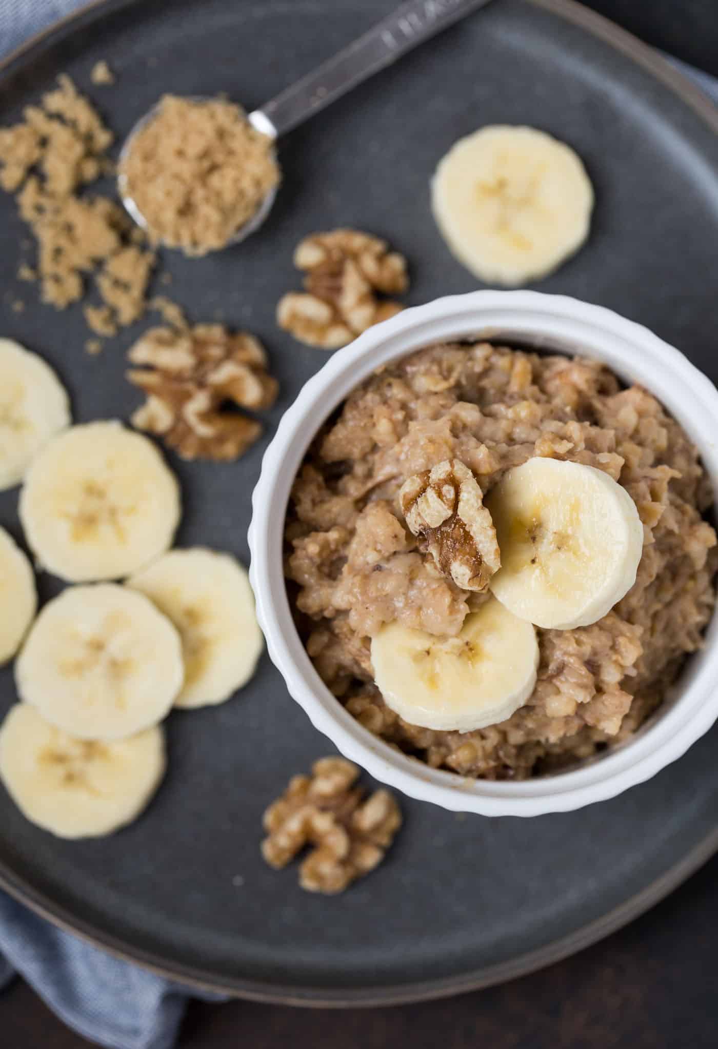 A bowl of oatmeal with banana and walnuts.