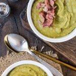 Two bowls of Slow Cooker Split Pea Soup with Ham and two spoons, with shredded ham.