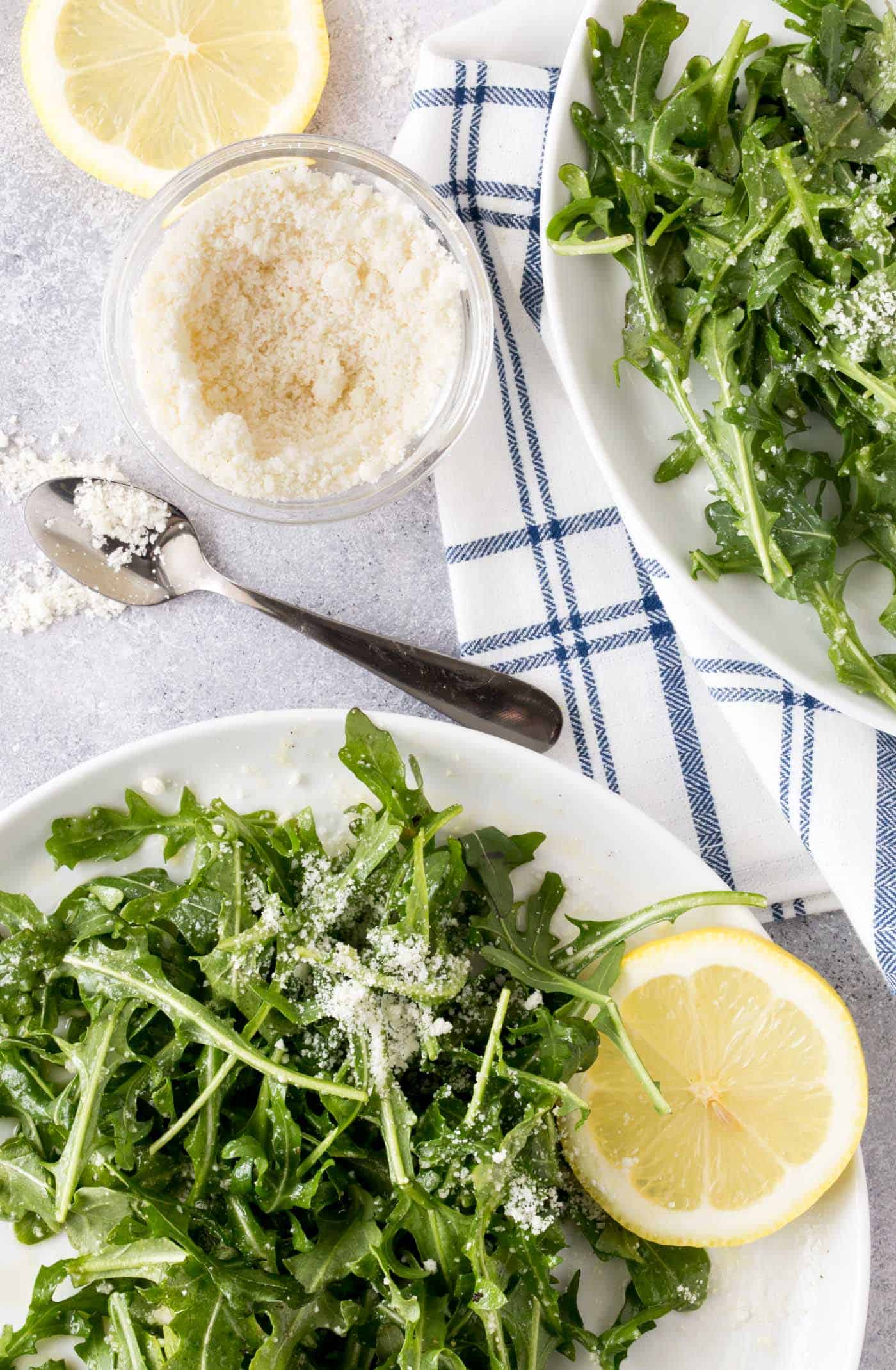  salad with lemon vinaigrette recipe on white plates with freshly grated parmesan cheese.