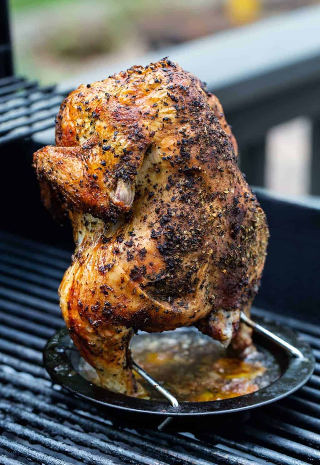  whole roasted chicken on a vertical roaster on grill.