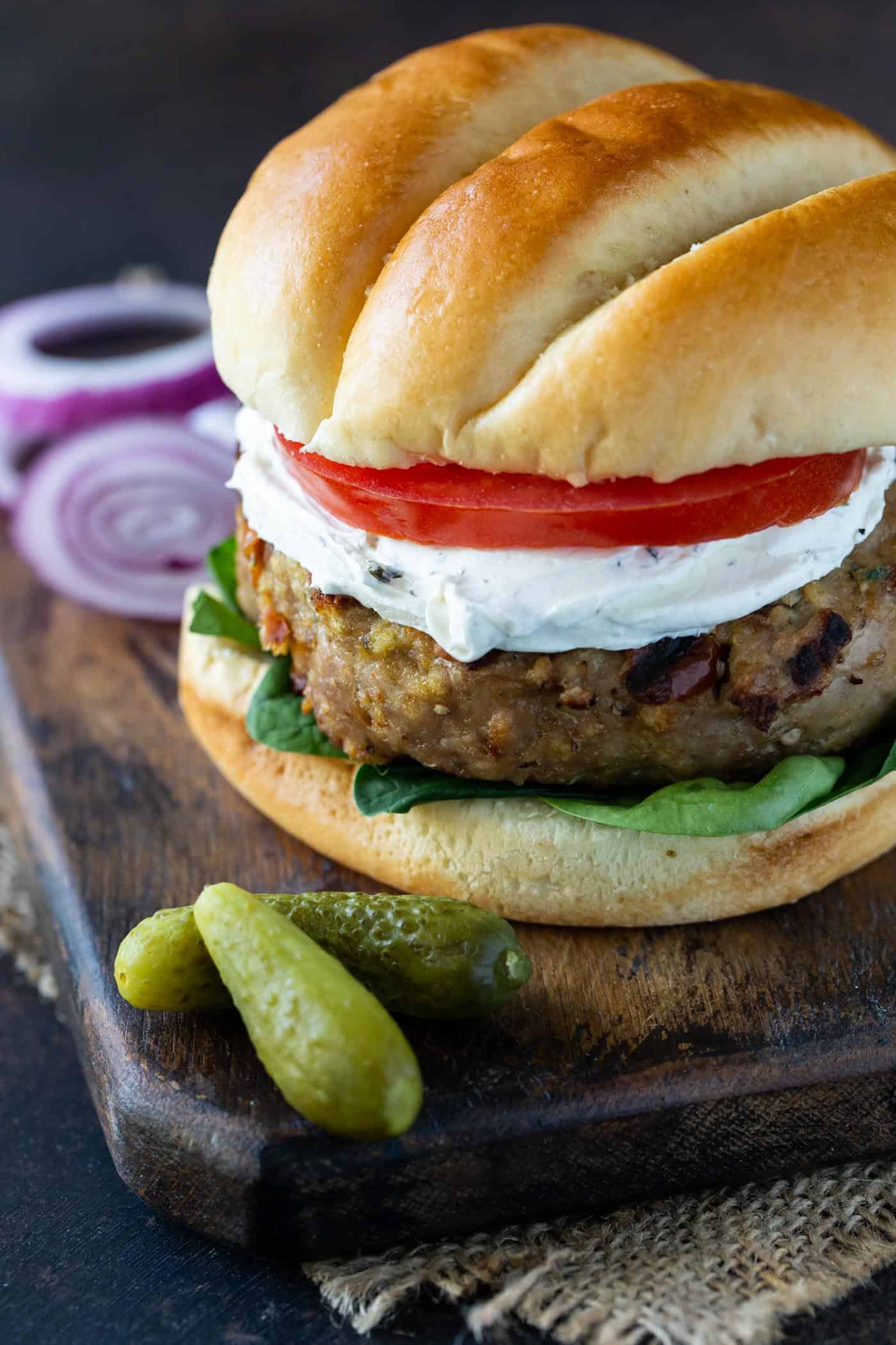 Grilled Turkey Burgers with Sun-dried Tomatoes and Goat Cheese garnished with lettuce, tomato and pickles.