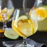 Close up shot of glass of Sangria Lemonade garnished with fresh apples, orange and lemon slices.