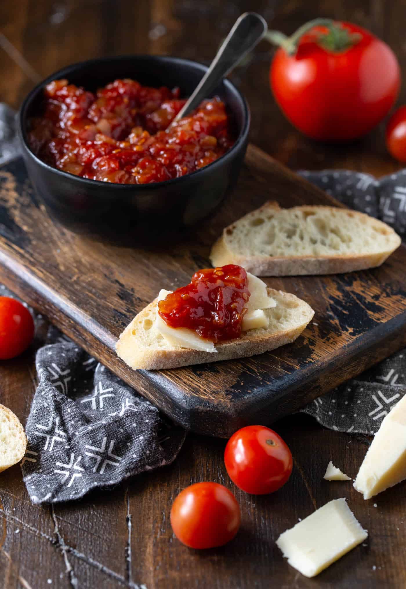 A bowl of fruit on a cutting board, with Tomato and Spread