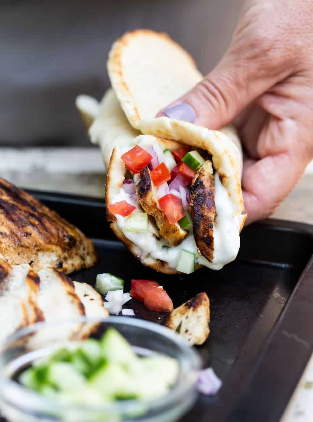 Close up image of hand holding an assembled easy gilled chicken gyro.