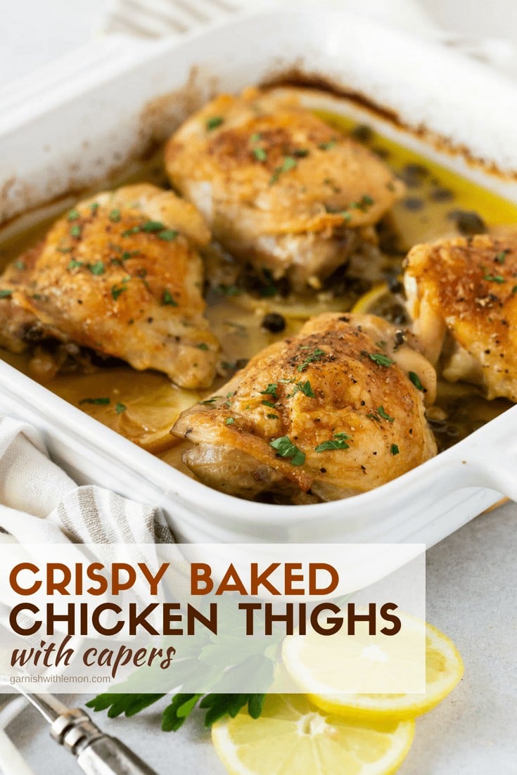 Chicken thighs with parsley and capers in white baking dish.