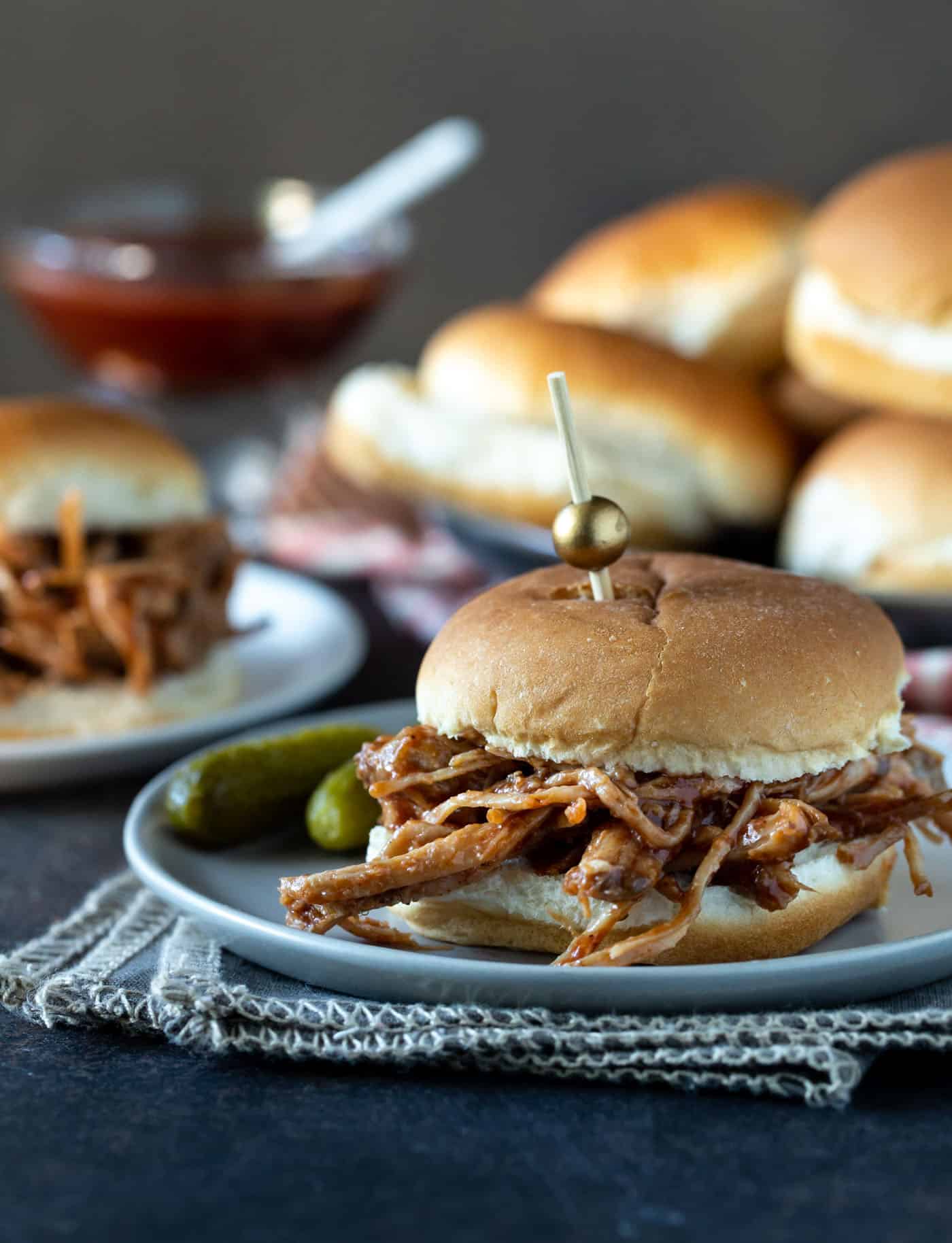 Pulled Pork on a bun with a toothpick skewered through the top.