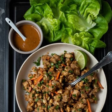 A bowl of  thai peanut chicken with lettuce cups.