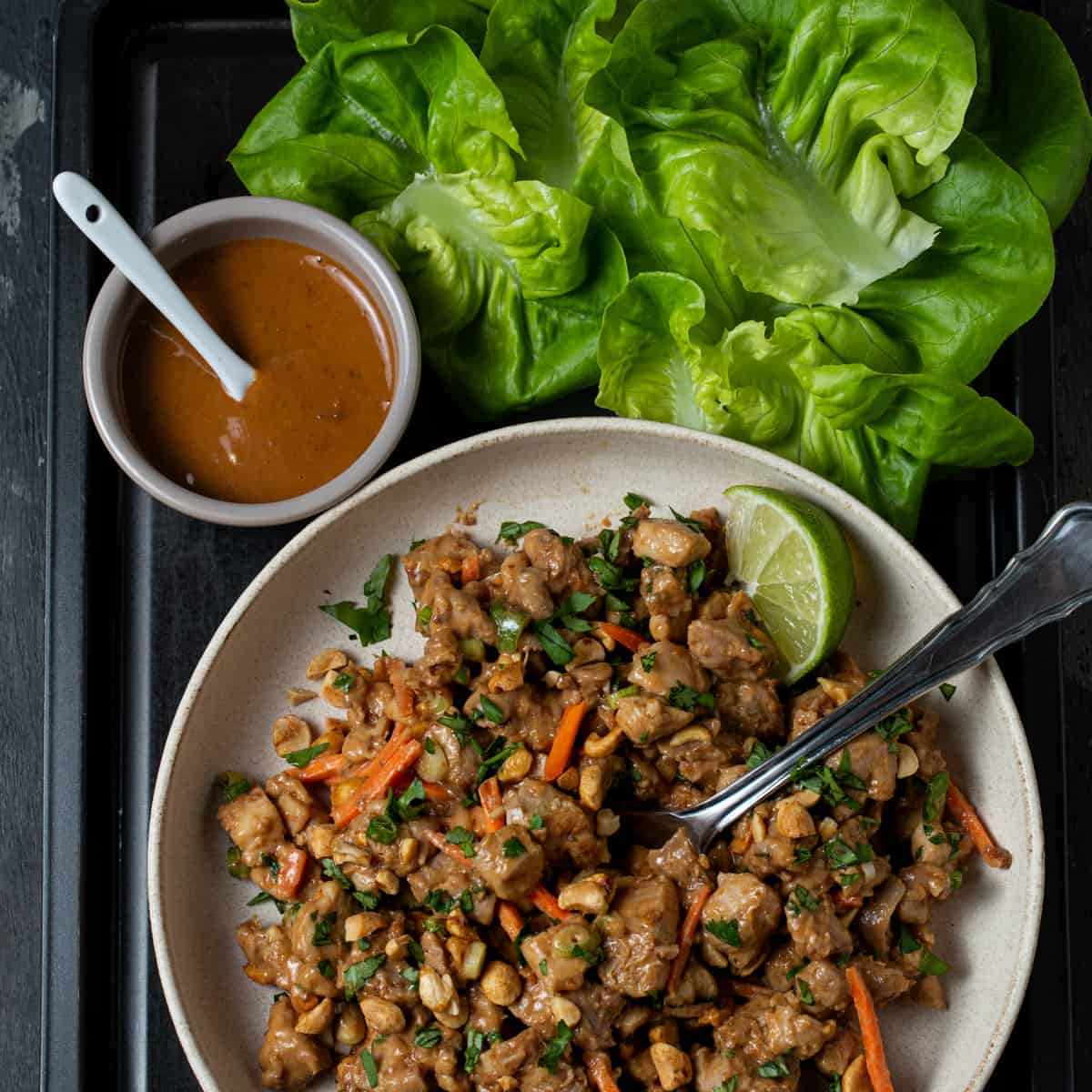 A bowl of  thai peanut chicken with lettuce cups.
