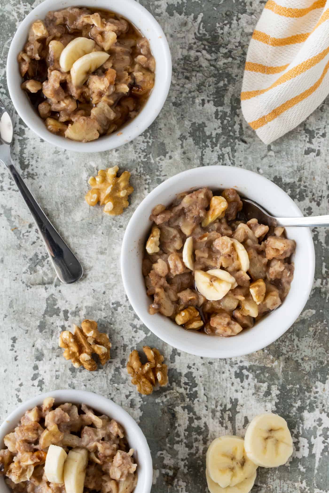 bowls of Banana Nut Baked Oatmeal Cups garnished with chopped walnuts and extra banana slices.
