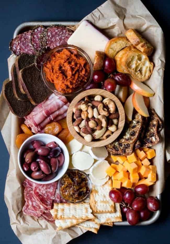 A tray of meats, cheeses, and fruits on a table.