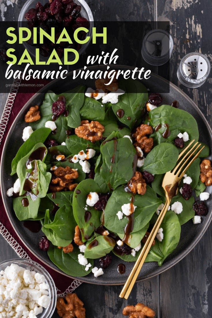 Spinach Salad with Balsamic Vinaigrette on a gray plate with candied walnuts for garnish.