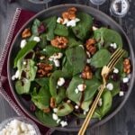 balsamic vinaigrette drizzled on spinach leaves on grey plate.