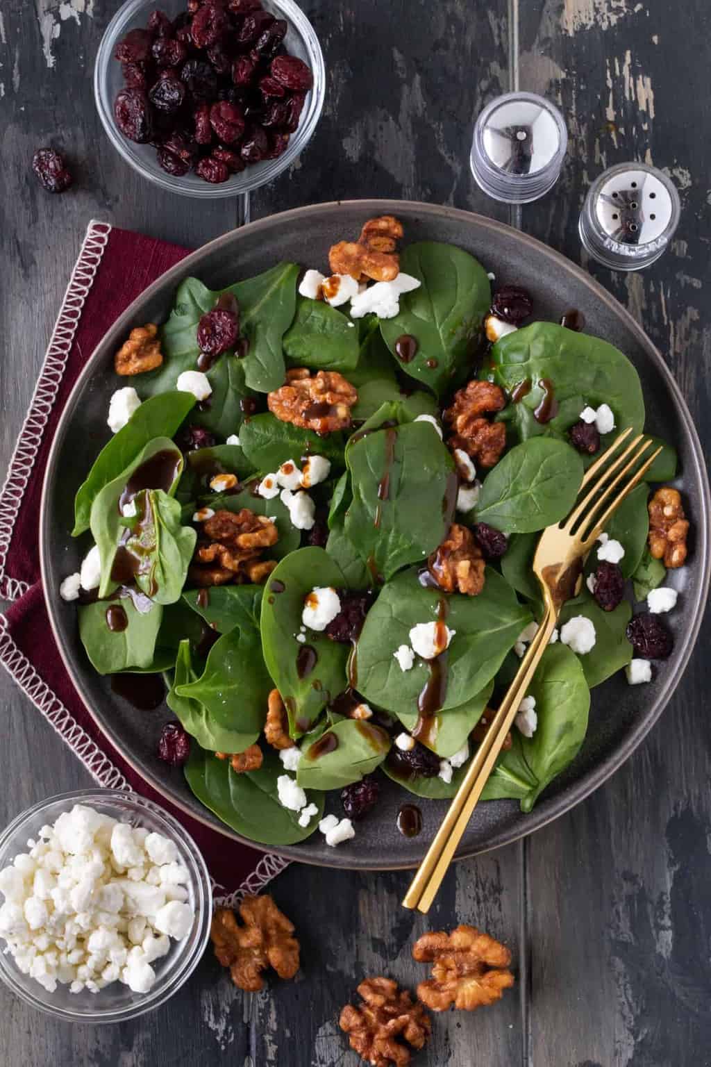 balsamic vinaigrette drizzled on spinach leaves on grey plate.