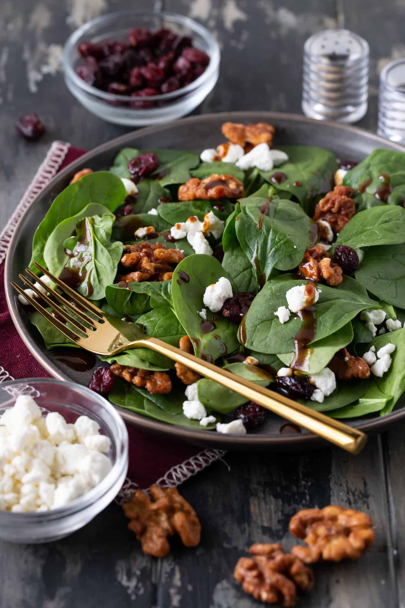 Spinach Salad on a  a grey plate with gold silverware.