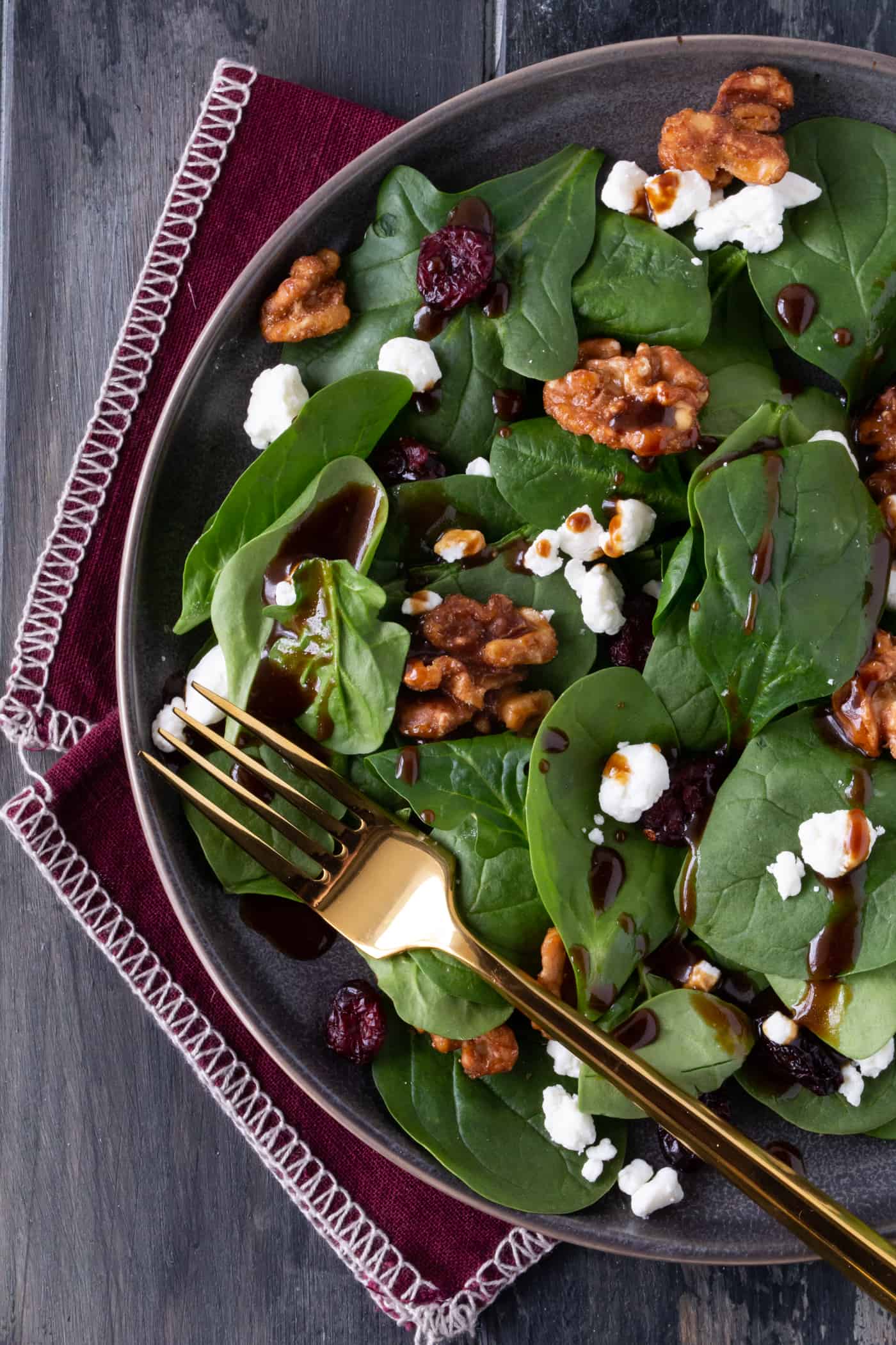 Close up of spinach Salad on a gray plate with gold silverware.