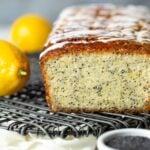 Loaf of lemon poppy seed bread drizzled with glaze on a cooling rack