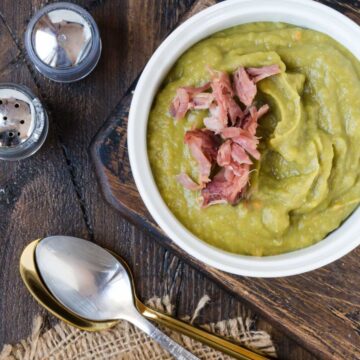 White bowl of split pea soup garnished with ham.