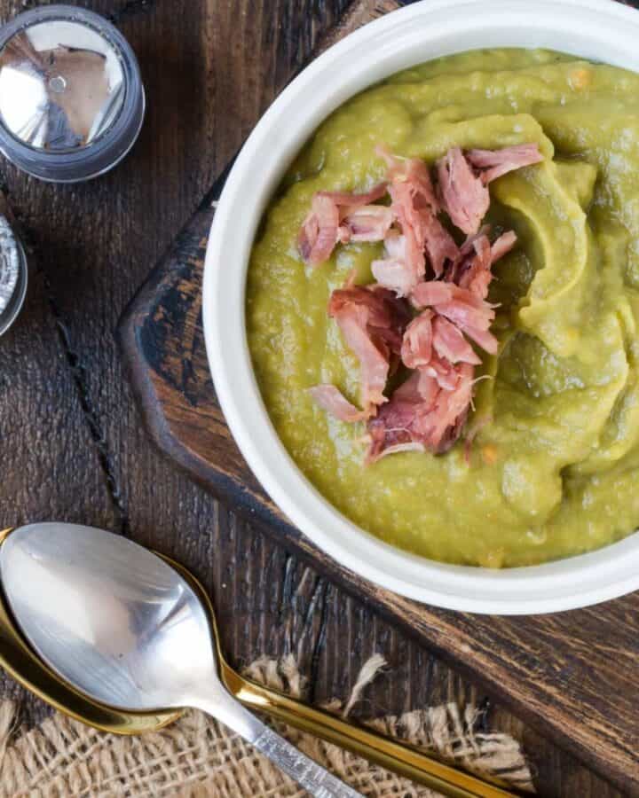White bowl of split pea soup garnished with ham.