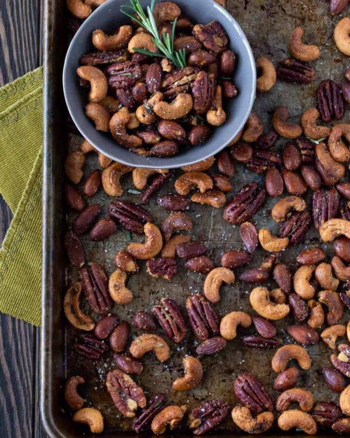 Nuts on a sheet pan with a small bowl filled with nuts.