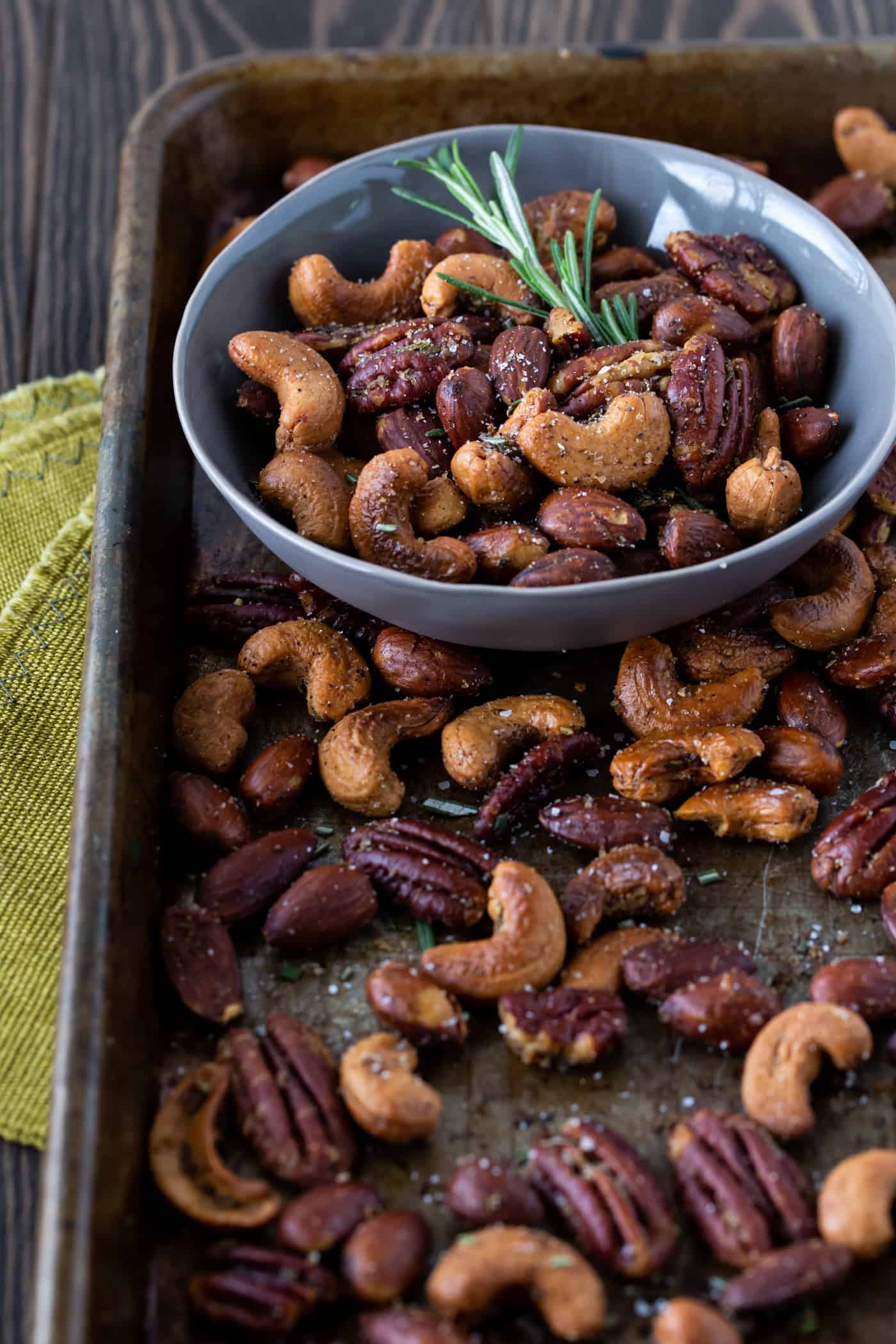 Roasted Nuts on a sheet pan with fresh rosemary for garnish.