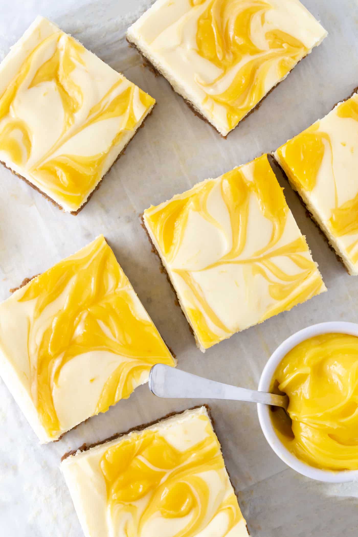 Close up of cut squares of Lemon Cheesecake Bars swirled with fresh lemon curd. 